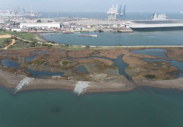 A view of an industrial area with boats in the water.